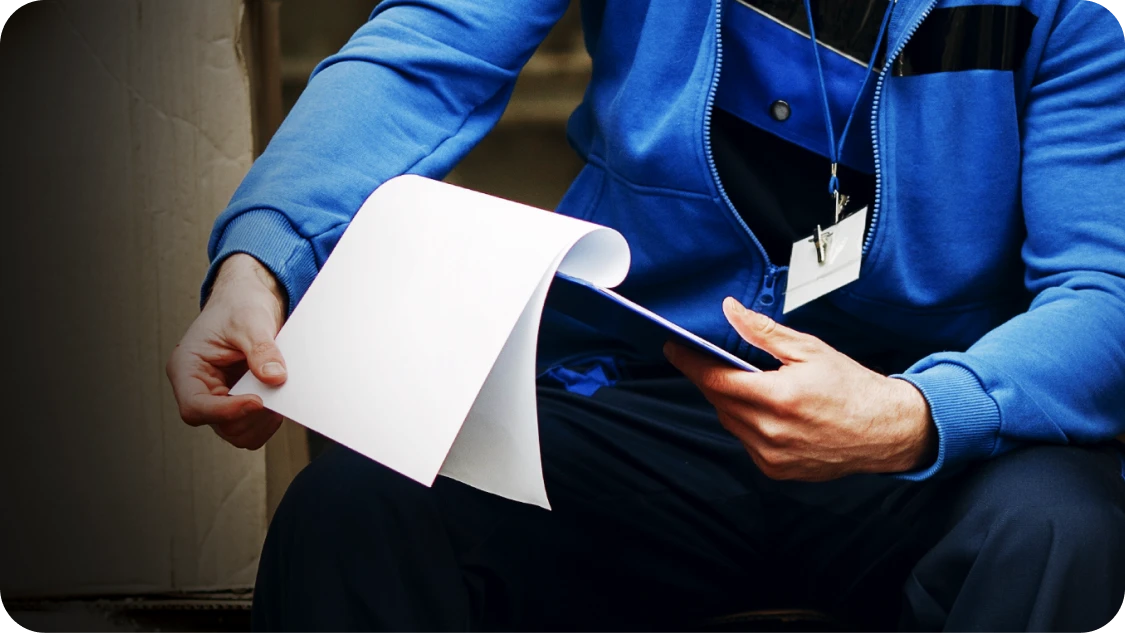 Event professional struggling with paper inventory list during late-night venue teardown. 