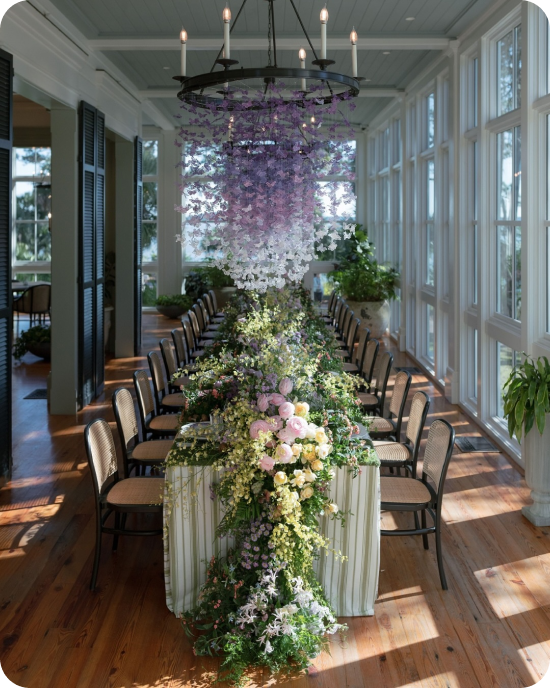 a cascading wisteria chandelier, lush garden runner, and caned chairs at a bridal luncheon